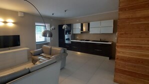 Une cuisine moderne avec des meubles de couleur sombre, un plan de travail blanc et un four encastré.