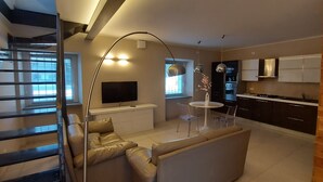 Une cuisine moderne avec un coin repas, un téléviseur et un escalier.