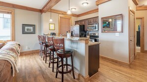 A kitchen with wooden beams, a bar area with stools, and a refrigerator.