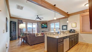 A spacious kitchen with a large island, wooden cabinets, and a ceiling fan.