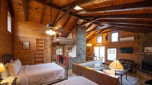 Een kamer in chaletstijl met twee bedden, een open haard, een stenen muur en een balkon.