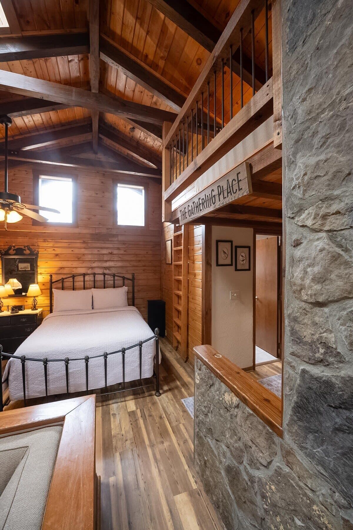 Een gezellig houten blokhut kamer met een bed, een klein bureau en een stenen muur.