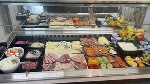 Un bufé con diversos alimentos, incluyendo carnes, quesos, frutas y verduras.