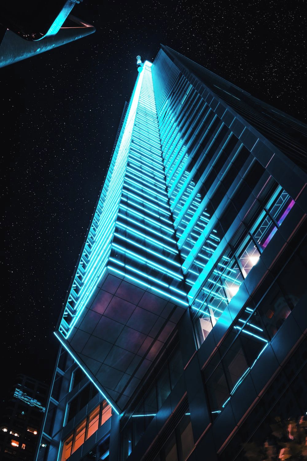 A tall building with a modern design, featuring a prominent vertical light strip and a glass facade.