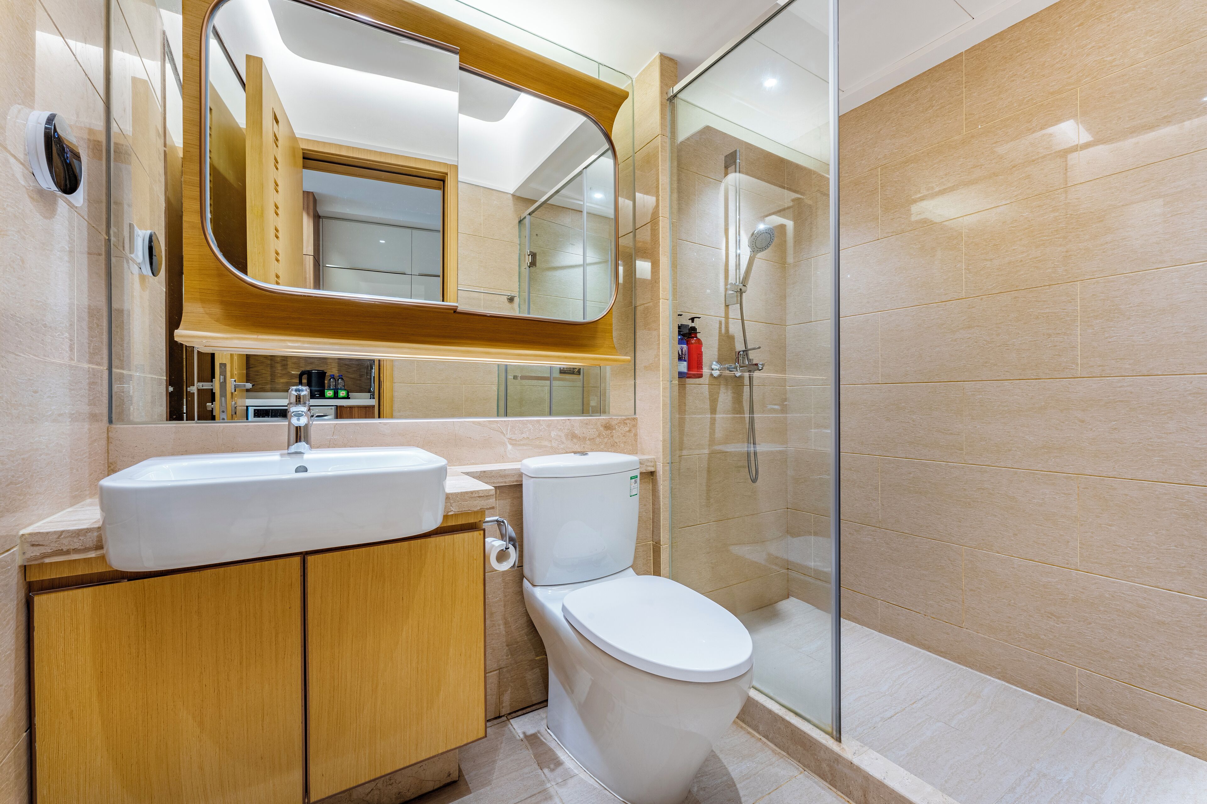 Un baño moderno con lavamanos, inodoro y ducha con mampara de vidrio.