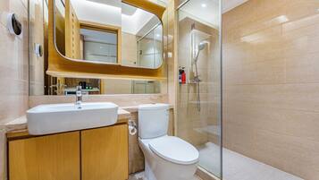 Un baño moderno con lavamanos, inodoro y ducha con mampara de vidrio.