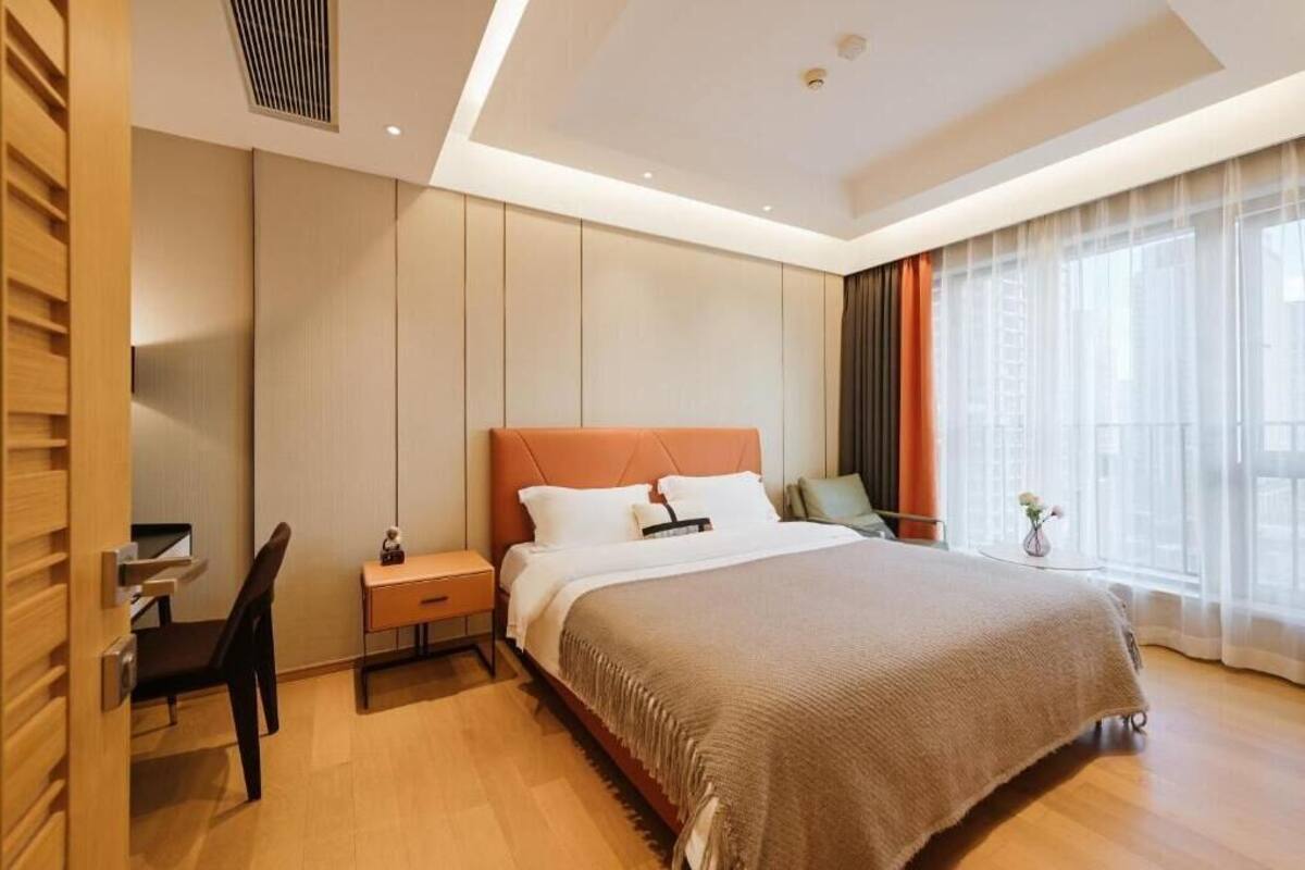 A modern hotel room with a large bed, a desk, and a chair.