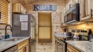 A kitchen with wooden cabinets, a stainless steel refrigerator, a microwave, and a stove.