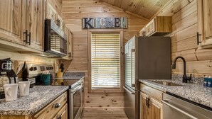 A wooden cabin-style kitchen with a central island, built-in appliances, and a 'KITCHEN' sign above the door. - Kerri's Cottage, Pickleball Court, Creek, WIFI, No Cleaning Fee (Cosby)