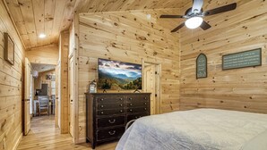Un dormitorio de cabaña de madera con cama, cómoda y ventilador de techo.
