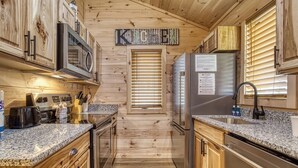 Une cuisine moderne avec des meubles en bois, des plans de travail en granit, des appareils électroménagers en acier inoxydable et une enseigne « Cuisine » accrochée au mur.