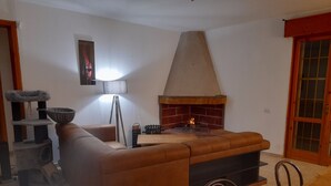 A living room with a brown leather sofa, a fireplace, a cat tree, and a dining table with chairs. - Villa Irene Nice Seaview (Lecce)