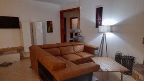 A living room with a brown sectional sofa, a wooden coffee table, a floor lamp, and a small side table. - Villa Irene Nice Seaview (Lecce)