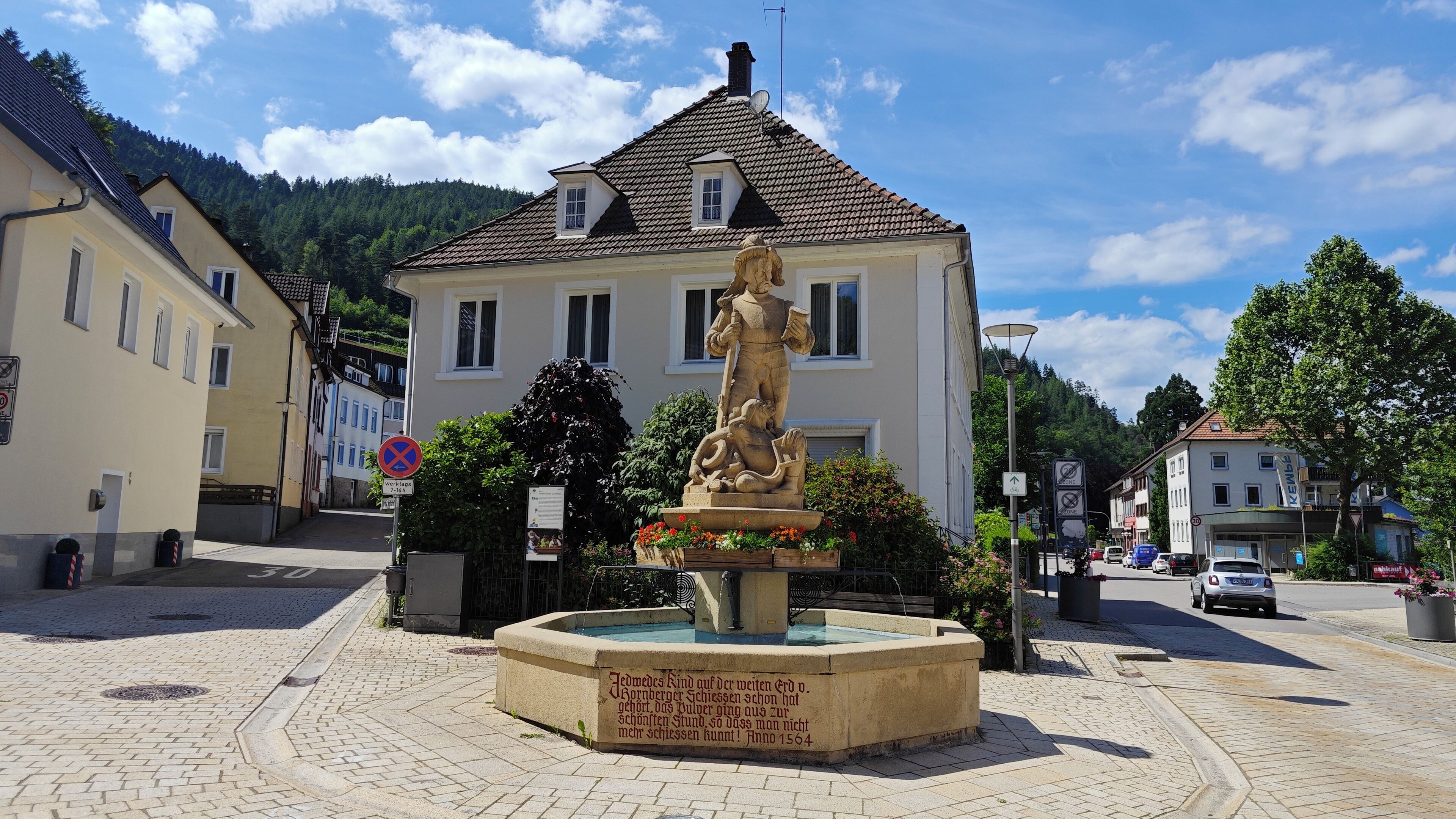 Una plaza pública con una estatua histórica, adoquinado y edificios tradicionales.