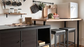 A modern kitchen with a dark wood cabinet, a wooden countertop, a white refrigerator, and a hanging pot rack. - Schwarzwaldraum Schlossblick (Hornberg)