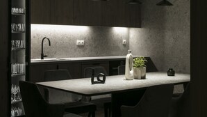A modern kitchen with a central island, pendant lighting, and a built-in wine rack. - Deluxe & Upscale Apartment in Athens (Athens)