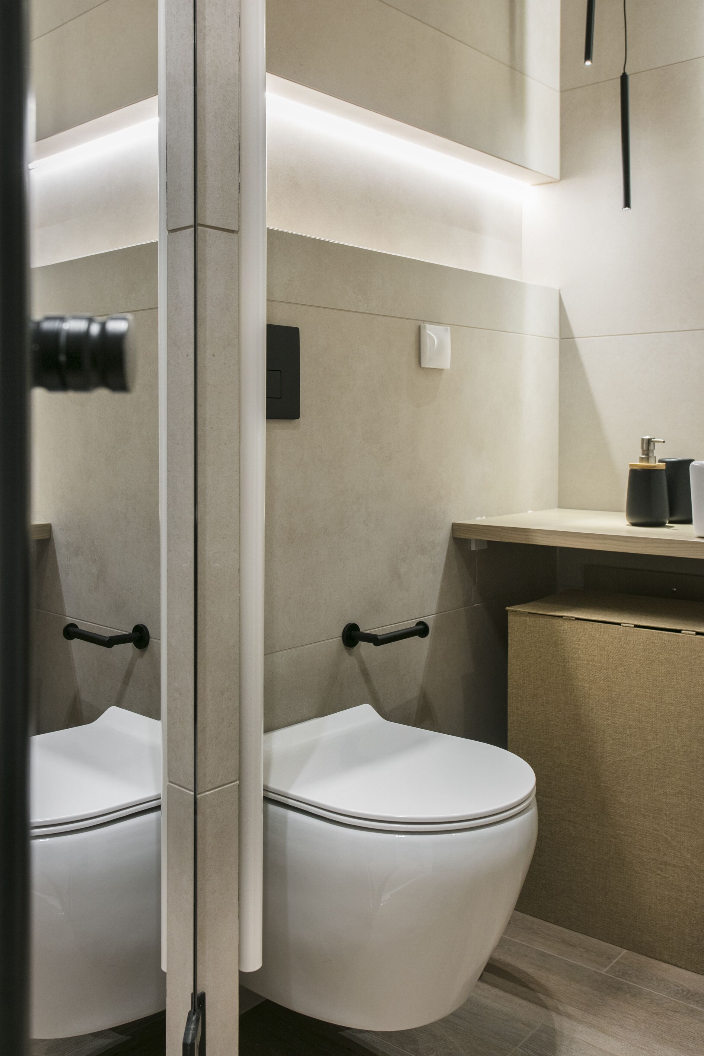 Un bagno moderno con due servizi igienici, un mobile bagno in legno e uno specchio.