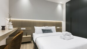 A modern hotel room with a bed, bedside table, chair, and a wall-mounted light fixture. - Deluxe & Upscale Apartment in Athens (Athens)