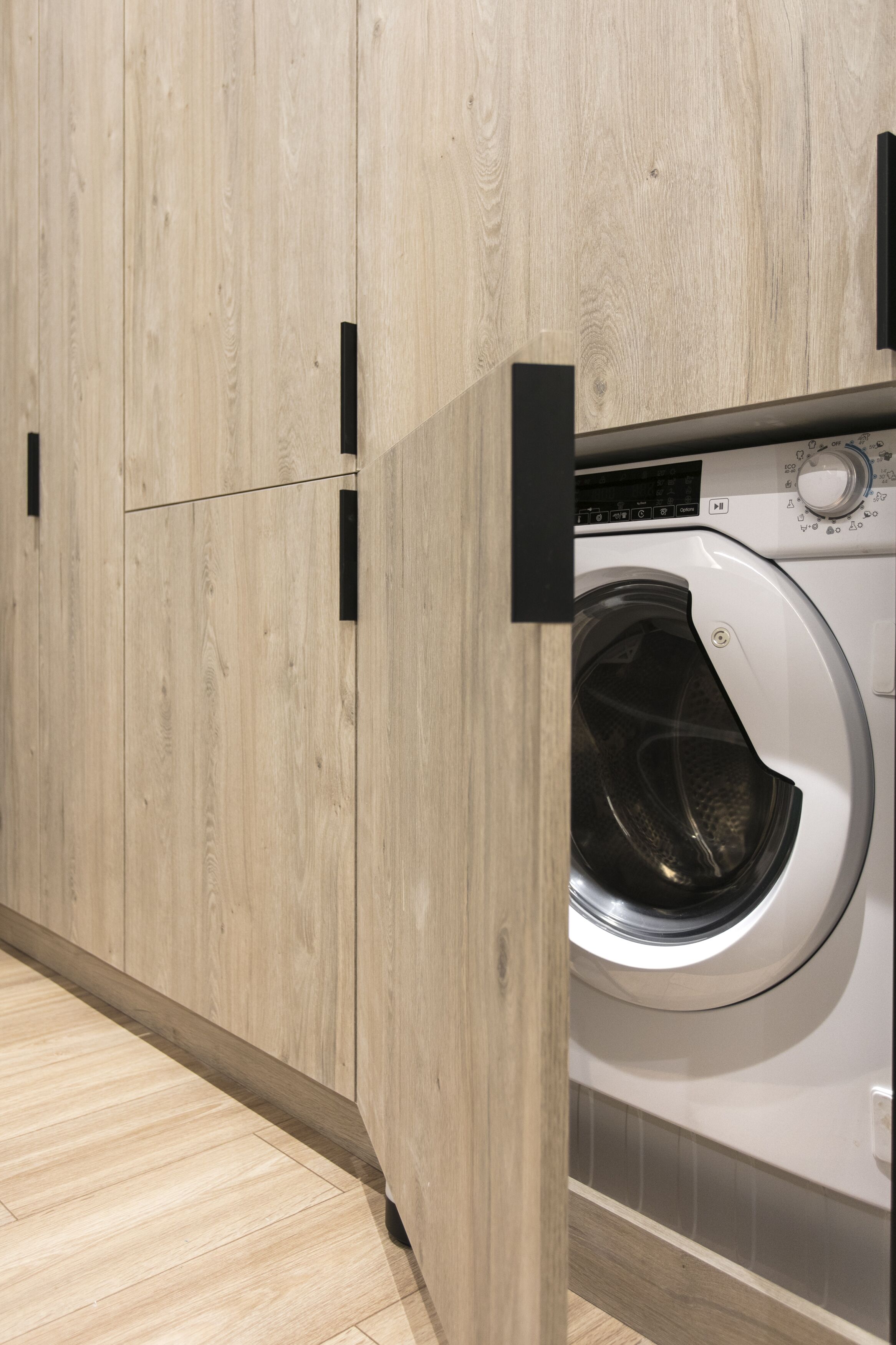 Ein moderner Waschraum mit Holzausstattung und einer Waschmaschine mit Frontlader.