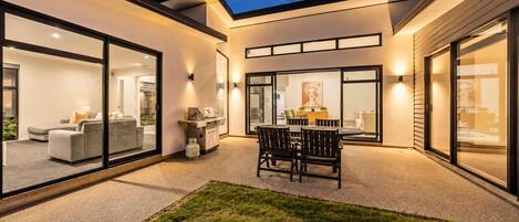Una casa moderna con patio, mobiliario exterior y zona de barbacoa.