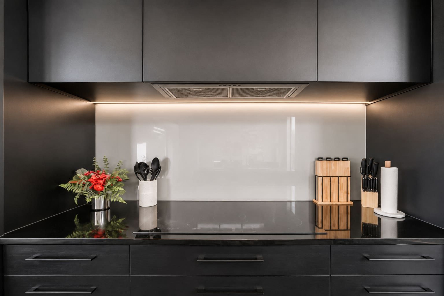 Eine moderne Küche mit schwarzer Arbeitsplatte, Edelstahlgeräten und schlichtem Design.