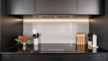 Eine moderne Küche mit schwarzer Arbeitsplatte, Edelstahlgeräten und schlichtem Design.