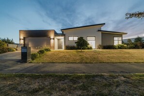 A modern two-story house with a garage, a well-maintained lawn, and a mailbox.