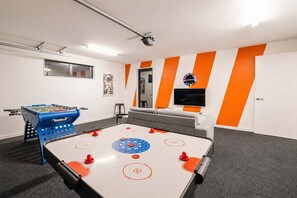 Une pièce équipée d’un baby-foot, d’une table de billard et d’un téléviseur.