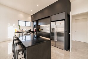 Una cocina moderna con una isla central, electrodomésticos de acero inoxidable y un diseño minimalista.