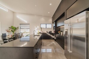 A modern kitchen with a central island, stainless steel appliances, and a view to the outdoors. - Zenith Escapes Your Quintessential 4BR Haven (Christchurch)