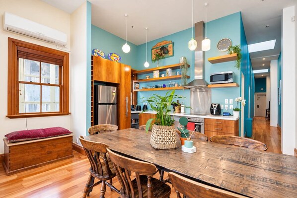 A modern kitchen with a wooden dining table, chairs, and a built-in refrigerator.