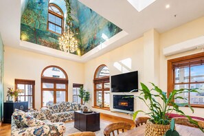 A spacious living room with a high ceiling, large windows, a fireplace, and a flat-screen TV. - The Bird's Nest | 2BR Loft | Lambton Quay (Wellington)