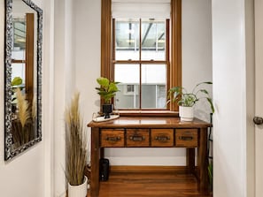 A wooden desk with drawers, a mirror, and two potted plants.