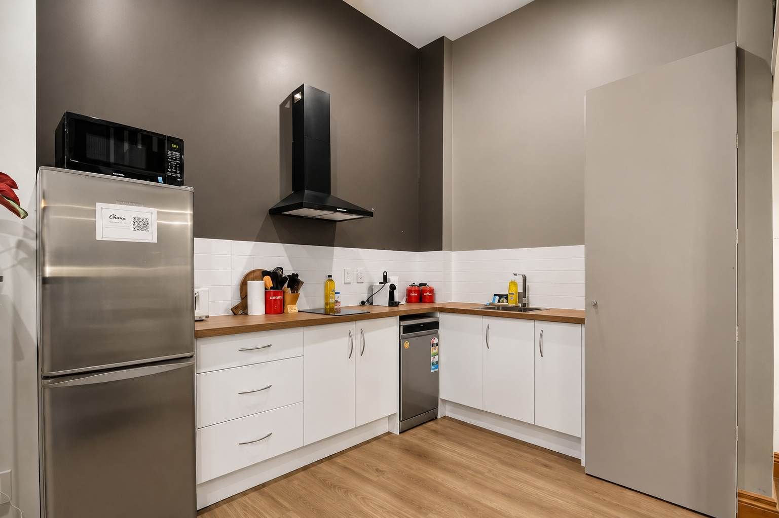 A modern kitchen with white cabinets, stainless steel appliances, and a wooden countertop.