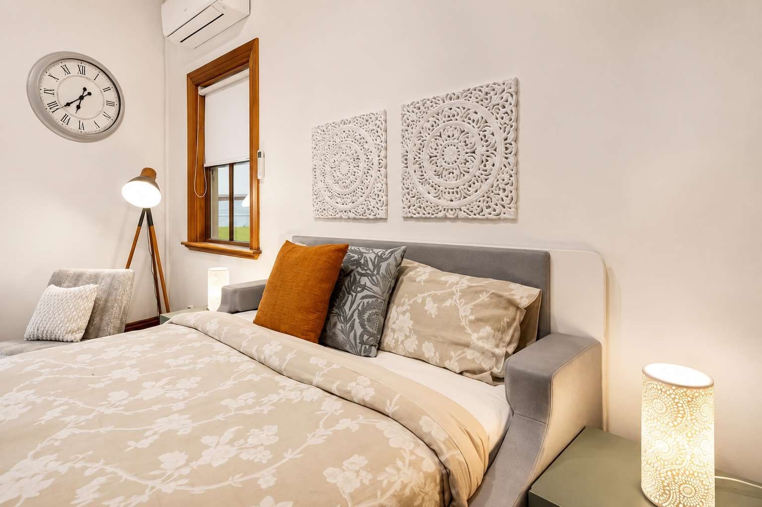 Un dormitorio con cama, lámpara de noche, reloj de pared y decoración mural.