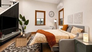 Un dormitorio moderno con cama, mesita de noche, lámpara y televisor.