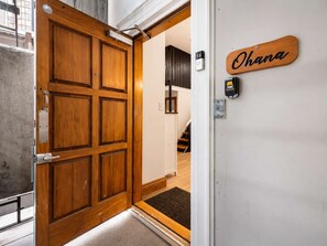 A wooden door with a metal handle, a nameplate reading 'Ohana,' and a security device on the wall.