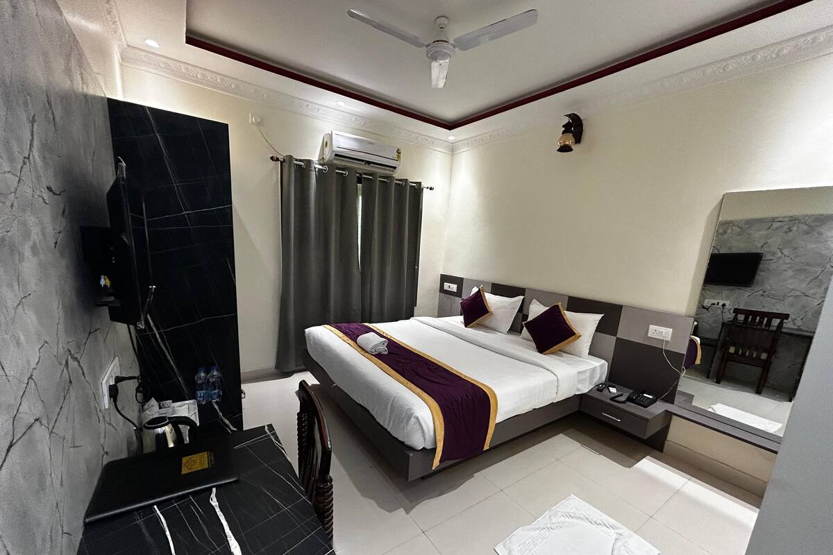 A hotel room with a bed, a bathroom, and a TV.