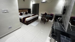 A hotel room with a bed, a desk, a chair, a TV, and a bathroom. - The Heritage (Dumka)