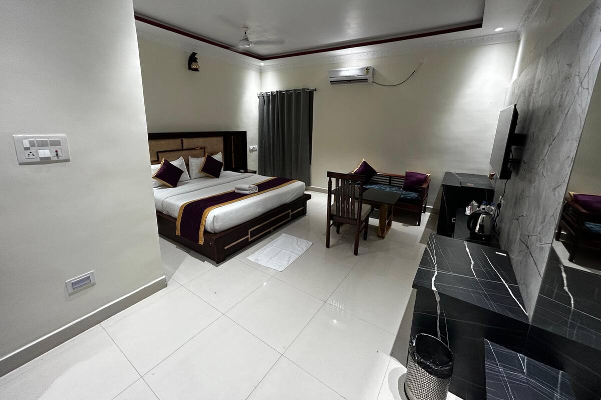 A hotel room with a bed, a desk, a chair, a TV, and a bathroom.