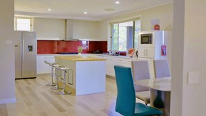 A modern kitchen with a central island, bar stools, and a dining table with chairs.