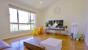A modern living room with a large window, a flat-screen TV, and plush toys.