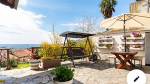 Une terrasse avec une balançoire, une table et des plantes en pot.