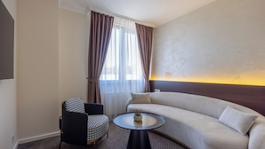 A modern hotel room with a sofa, a chair, and a round table. - Nobel West Hotel (Belgrade)