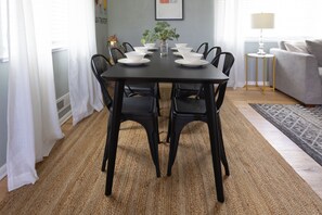 A dining table with chairs, a vase with a plant, and a framed picture on the wall.