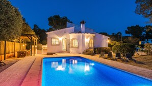 A house with a swimming pool, a covered patio, and a well-lit entrance. - Quiet 3 Bedroom Family Villa (Javea / Xàbia)