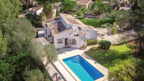 A white villa with a swimming pool, surrounded by lush greenery and other houses. - Quiet 3 Bedroom Family Villa (Javea / Xàbia)