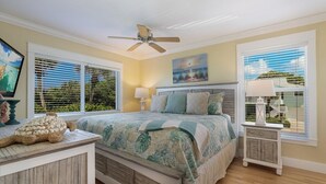 A bedroom with a bed, a ceiling fan, a painting, and a window with blinds. - Beachfront, Breathtaking Gulfviews with Resort Pool and Spectacular Sunsets. (HOLMES BEACH)