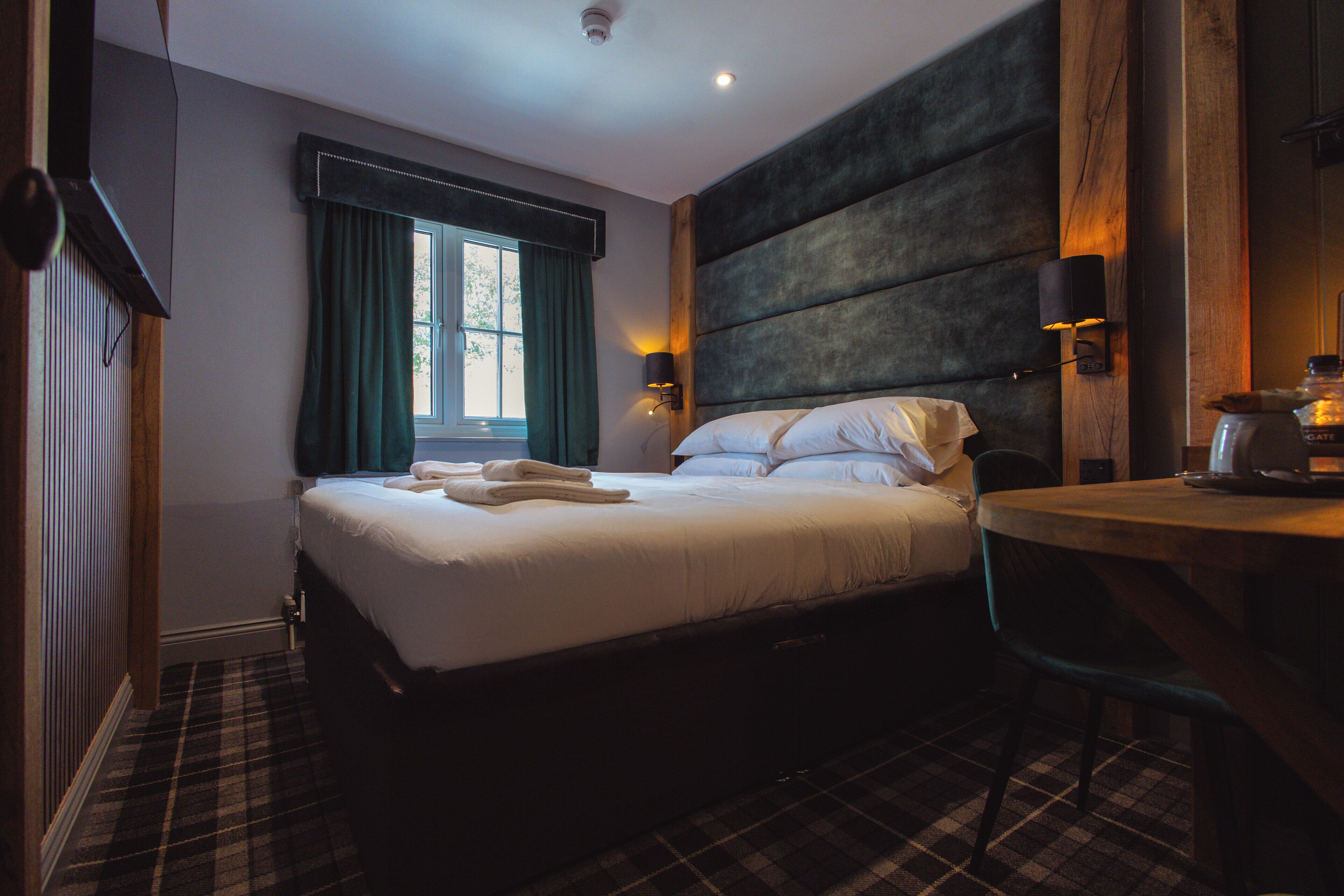 Une chambre d’hôtel avec un lit, un bureau et une fenêtre avec des rideaux.