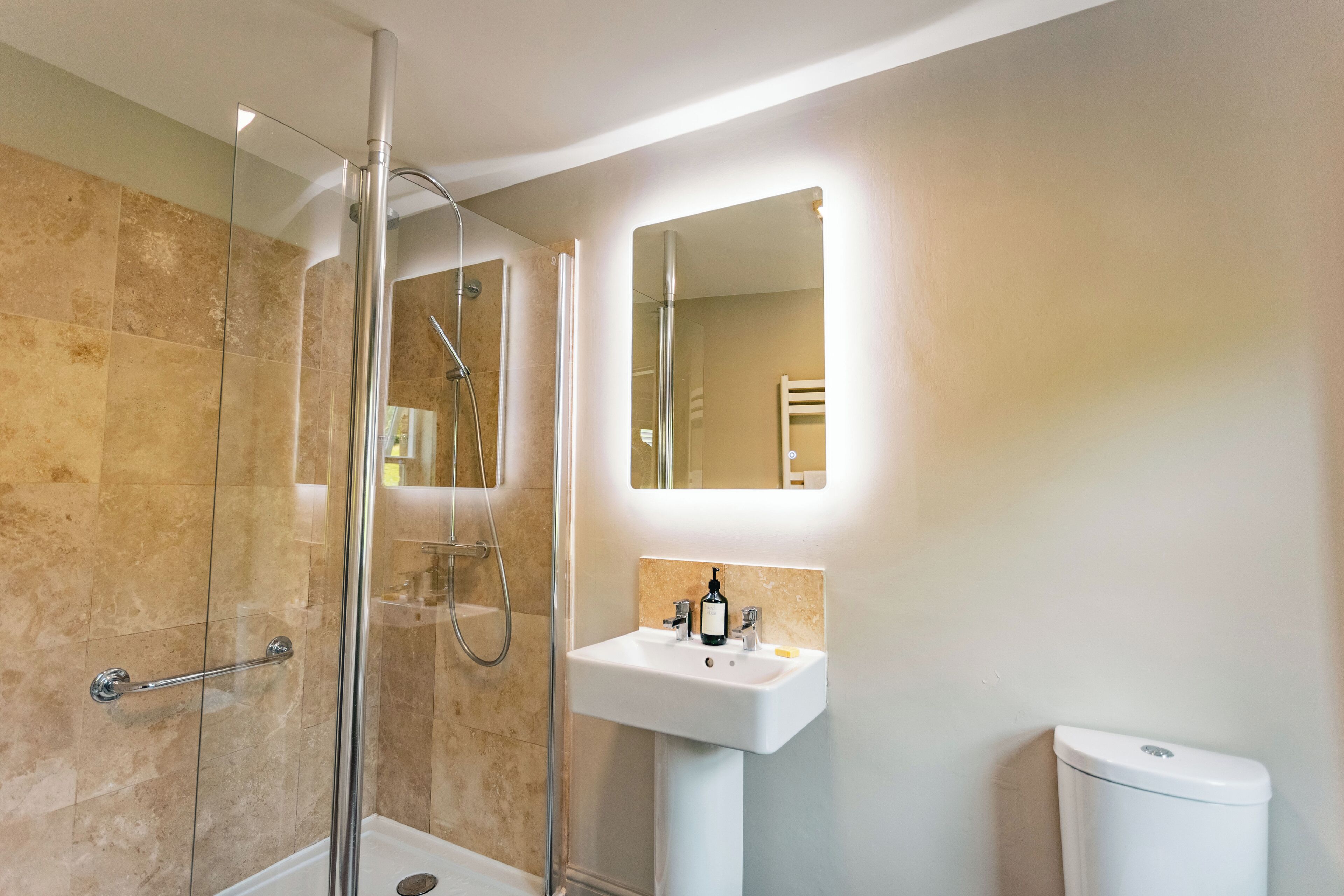 A modern bathroom with a glass shower enclosure, a white sink, and a toilet.